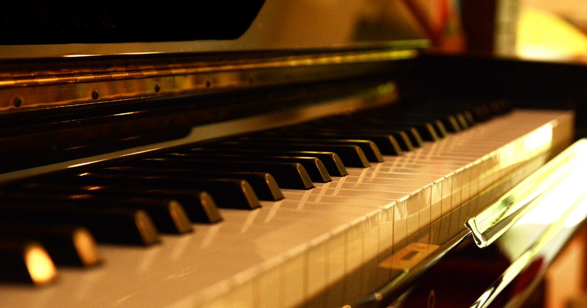 夕日に照らされたアップライトピアノの鍵盤