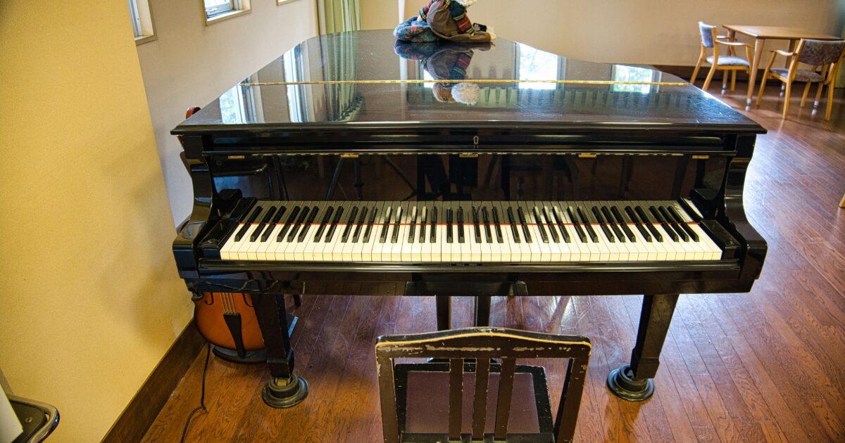 部屋に置かれた黒いグランドピアノと椅子