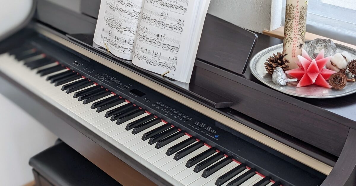 楽譜と飾りが置かれた電子ピアノの鍵盤
