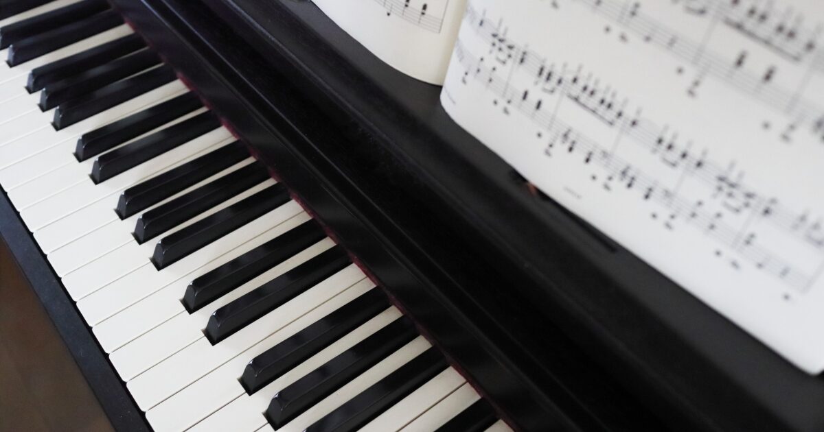 楽譜が置かれた黒いアップライトピアノの鍵盤