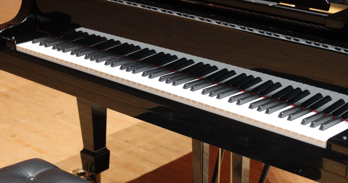 ステージ上の黒いグランドピアノの鍵盤とペダル