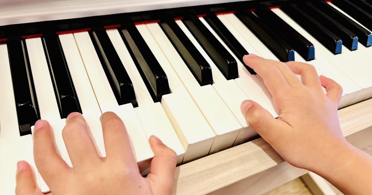 子供の手が電子ピアノの鍵盤を演奏している様子