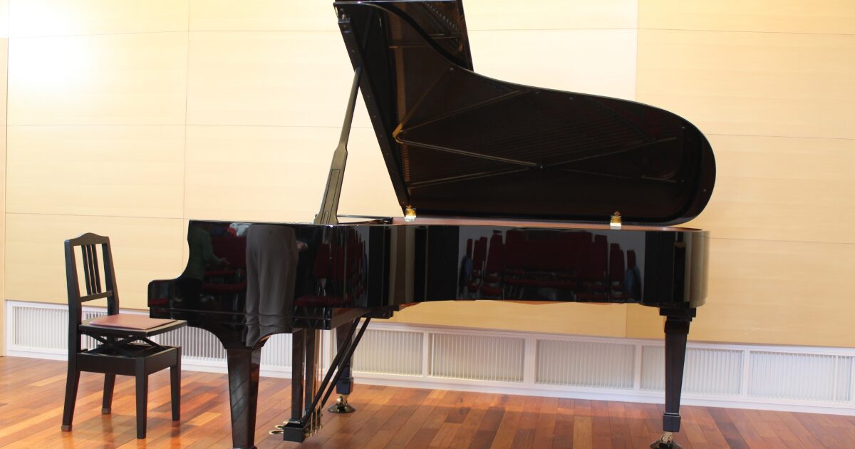 木製の床に置かれた黒いグランドピアノと椅子