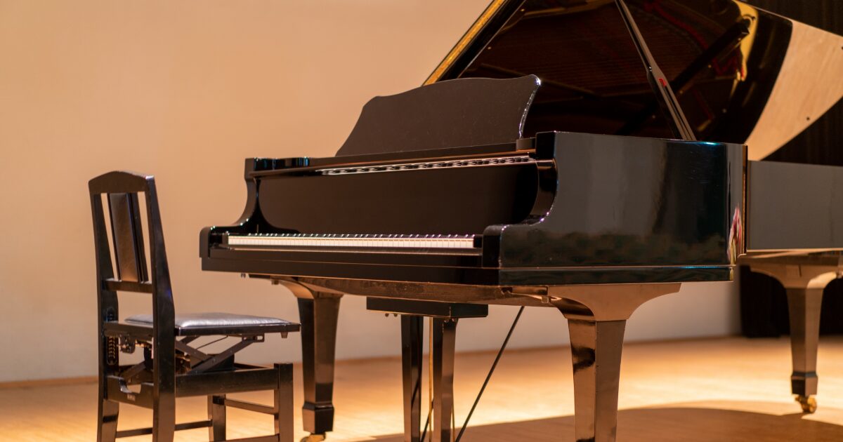 ステージ上に置かれた黒いグランドピアノと演奏用椅子