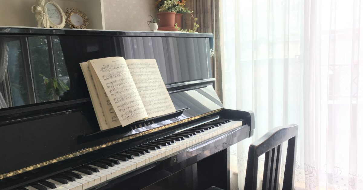 アップライトピアノと楽譜が置かれた明るい部屋の一角