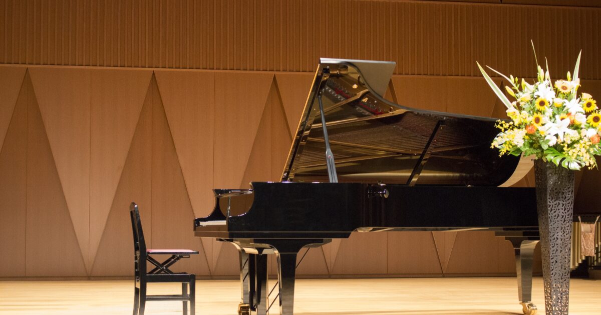 コンサートホールのステージに置かれたグランドピアノと花