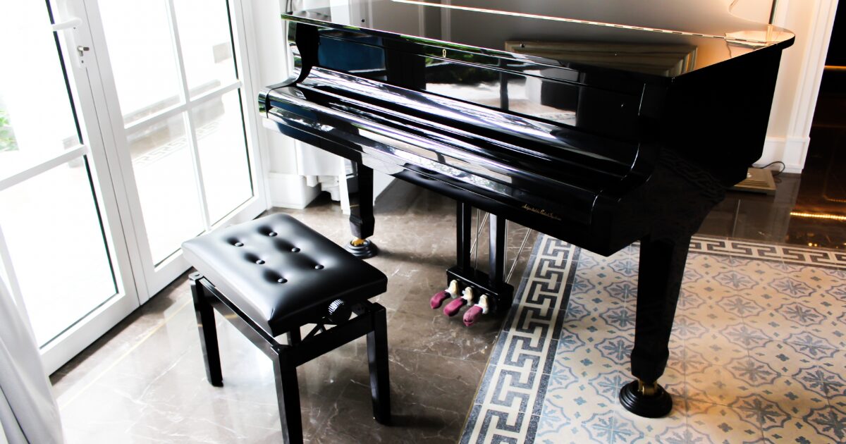 日差しの入る部屋に置かれた黒いグランドピアノと椅子