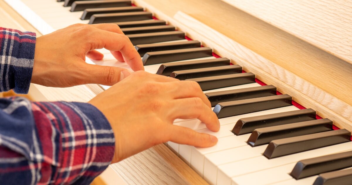 木目調の電子ピアノを演奏する手元のクローズアップ