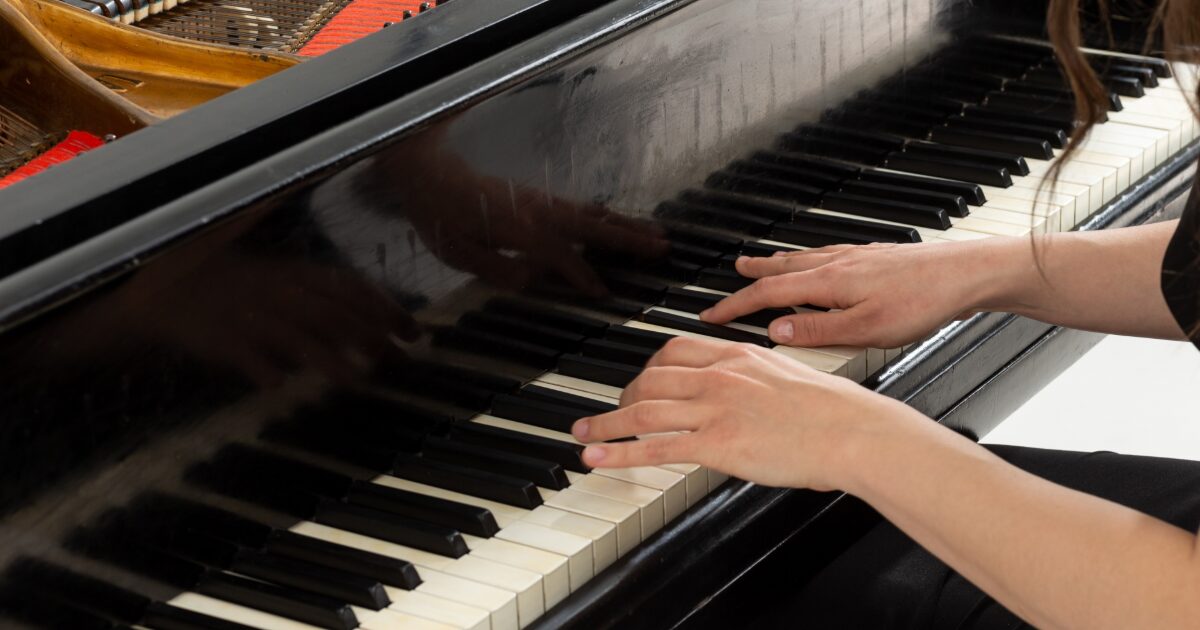 グランドピアノを演奏する女性の手元のクローズアップ