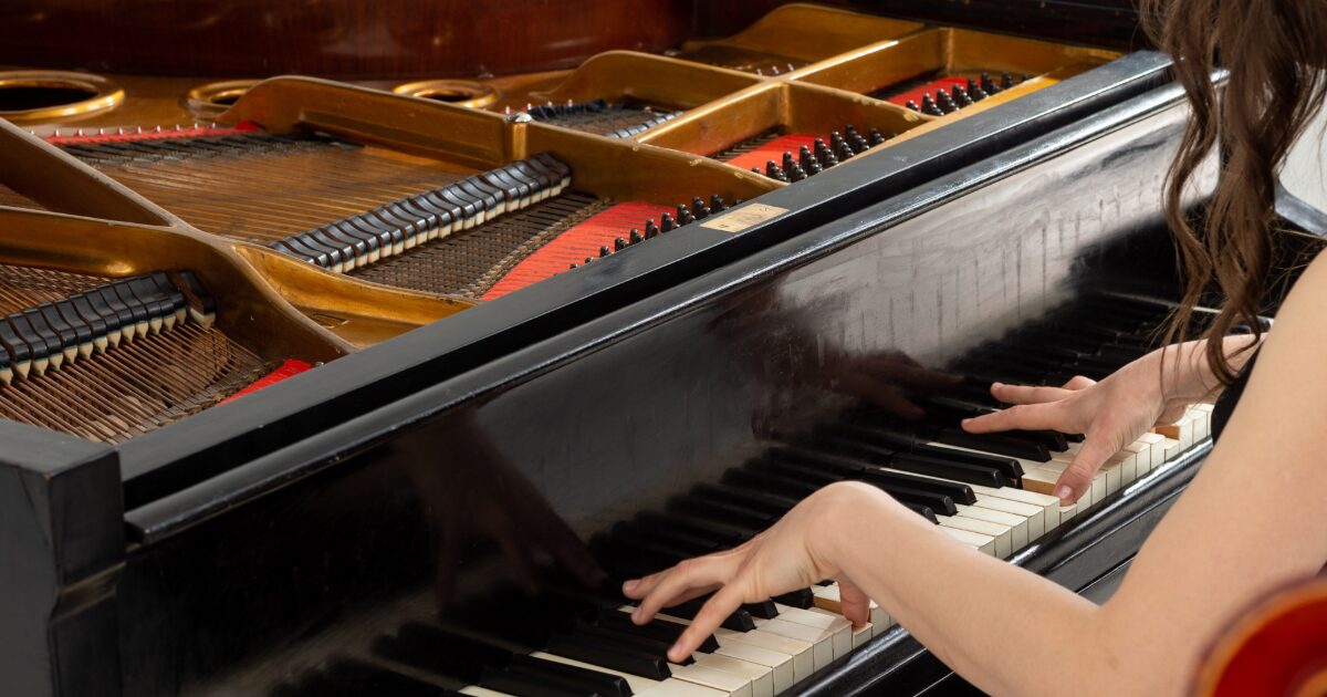 グランドピアノを演奏する女性の手元と内部構造