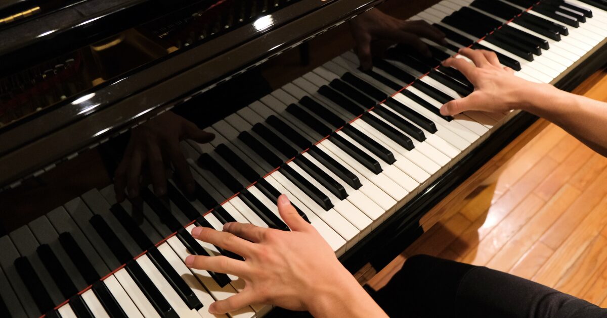 グランドピアノを弾く両手の上からの視点