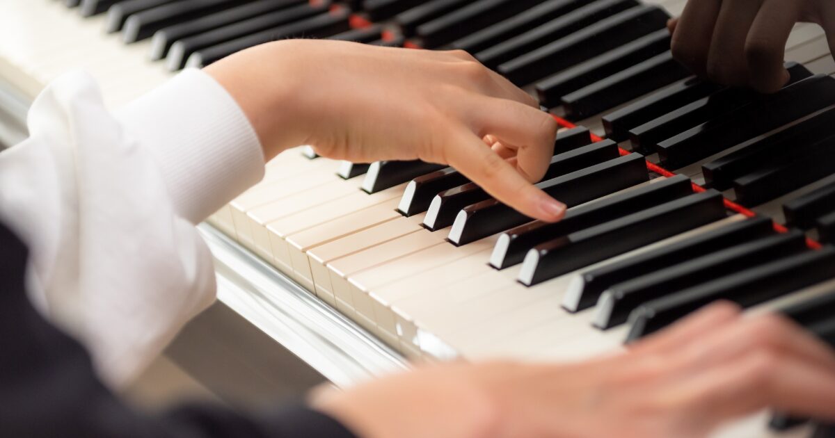白い服を着た人がピアノを演奏している手元のクローズアップ