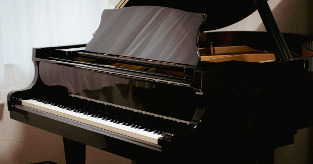 室内に置かれた黒いグランドピアノの全体像